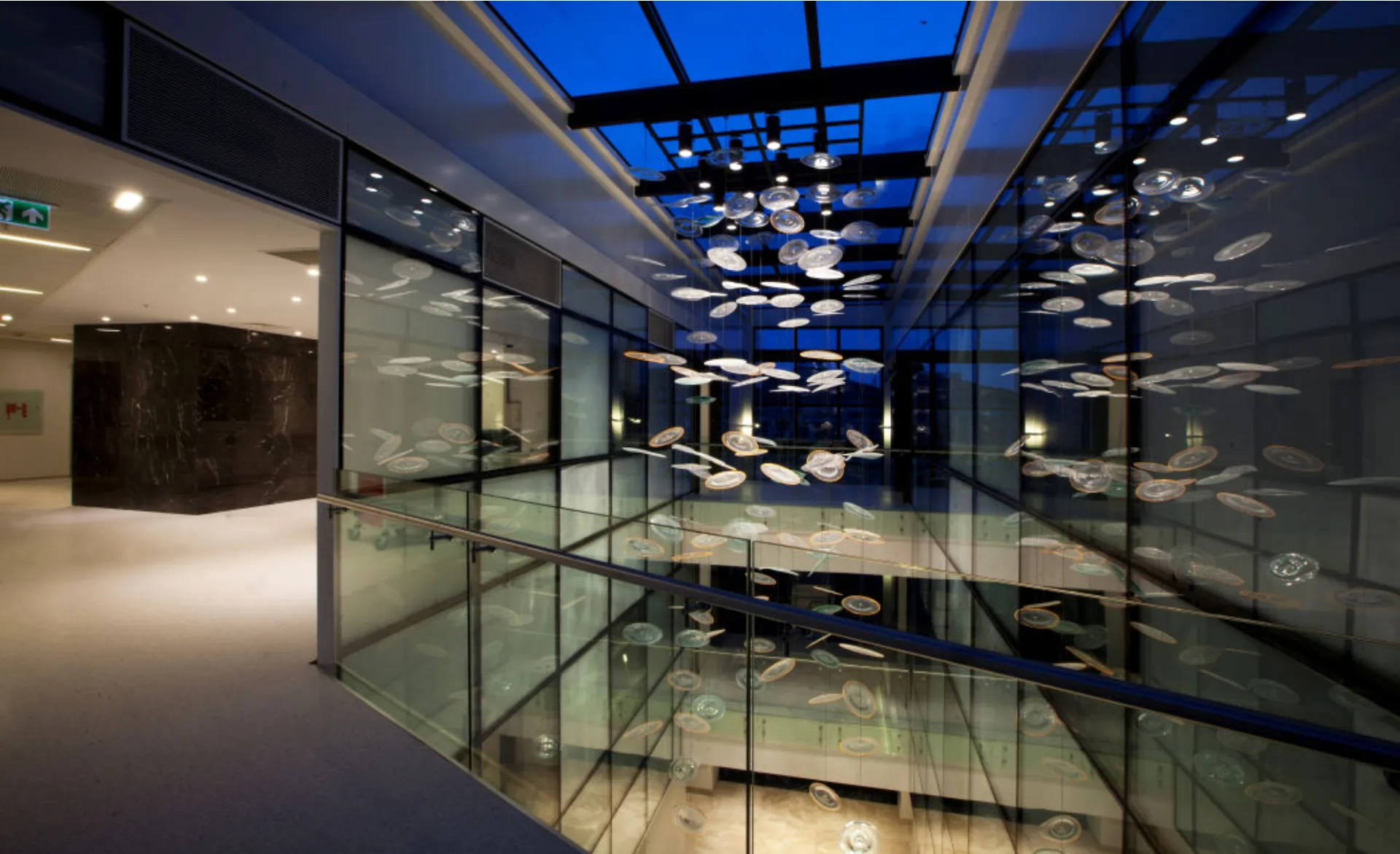 Glass atrium with suspended lighting seen from a floor corridor at NB Hospital, Acıbadem, Kadıköy
